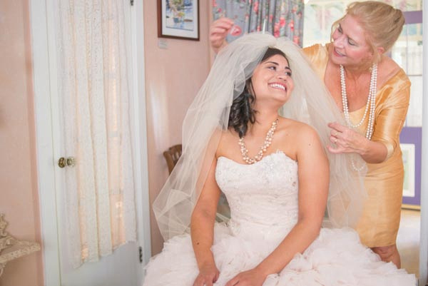 Mother helping smiling bride get ready before wedding at The Seasons Bed & Breakfast in Placerville.