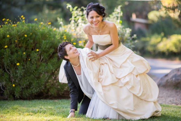 Funny bride poking out underneath other bride's dress at The Pavilion at Redwood Estates.